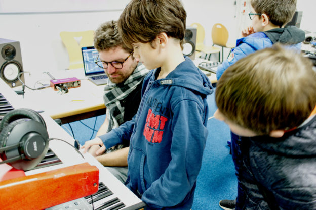 photo d'un élève jouant sur un synthé, dans uen salle de classe transformée en studio