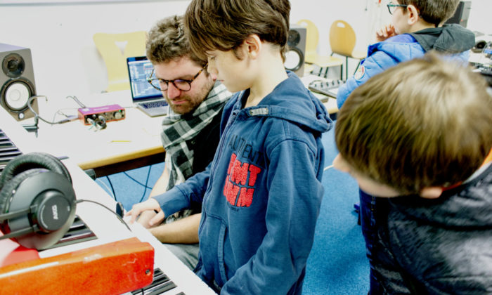photo d'un élève jouant sur un synthé, dans uen salle de classe transformée en studio